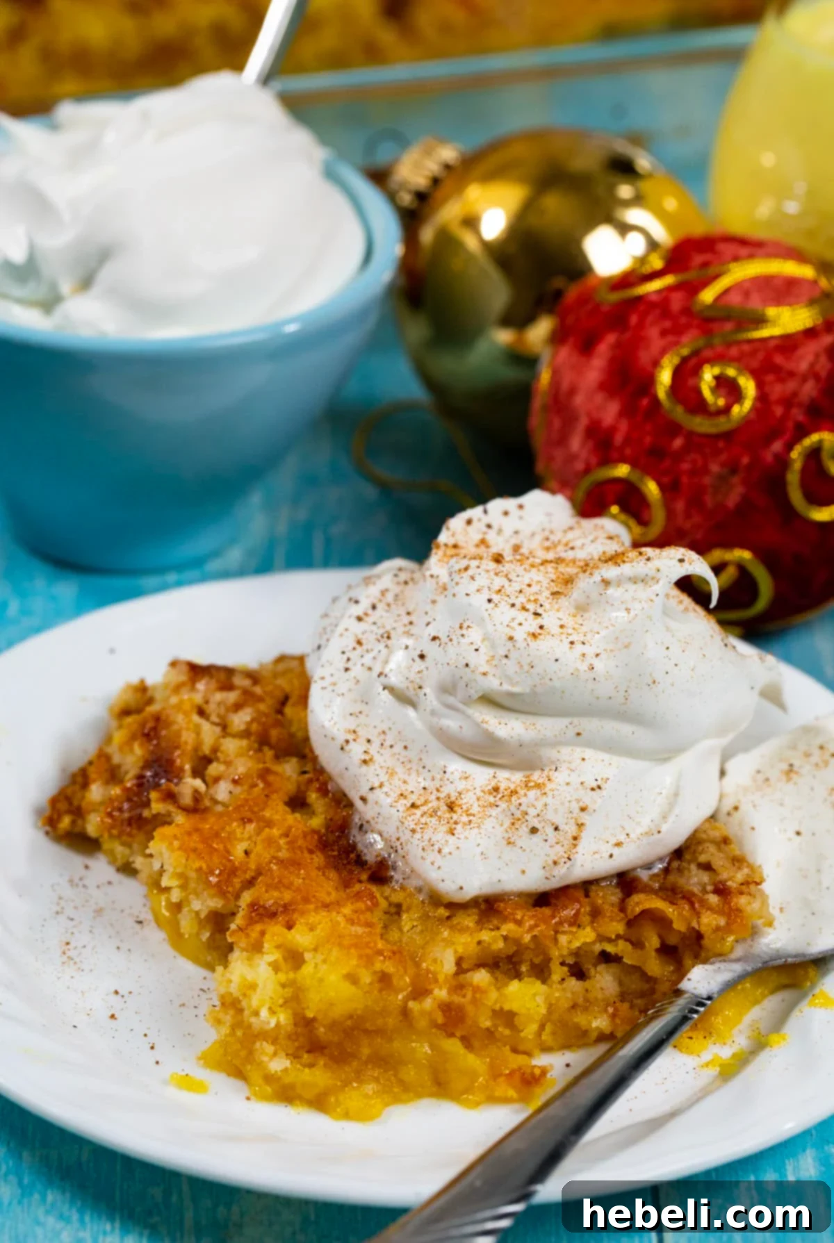 A single serving of warm Eggnog Dump Cake on a plate, garnished with whipped cream and a sprinkle of nutmeg.