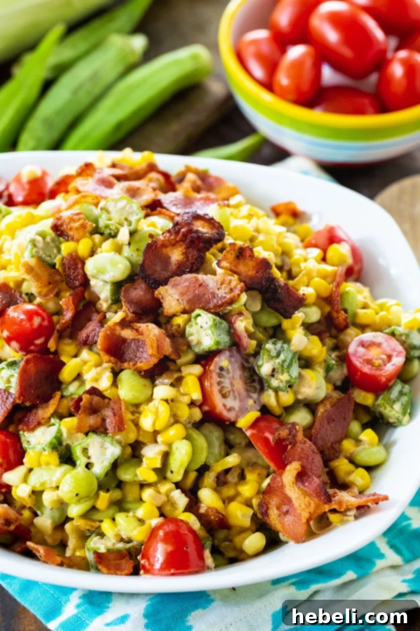 Succotash served in a white bowl, with fresh grape tomatoes artfully arranged nearby, highlighting the freshness of the ingredients.
