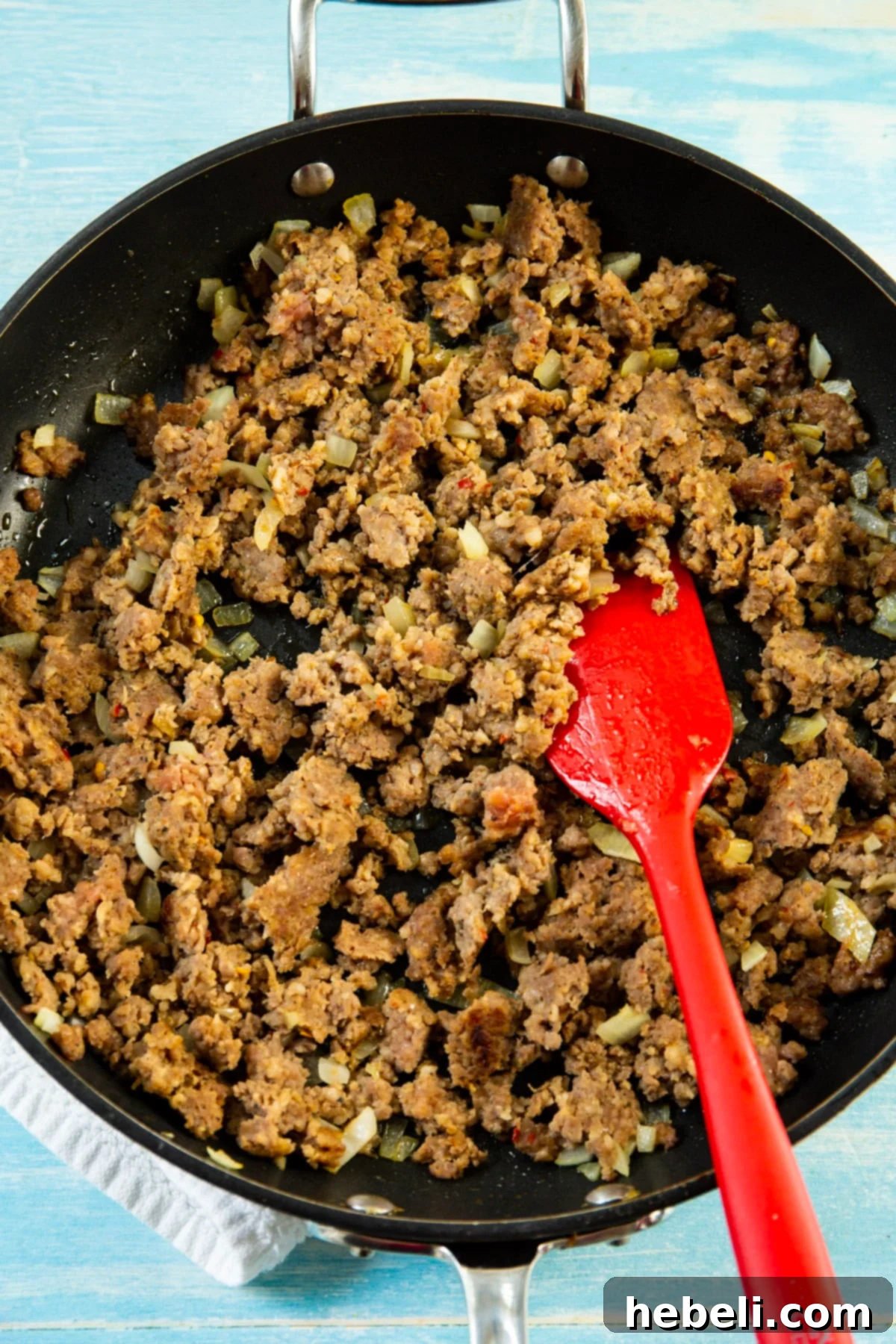 Southern Comfort Pea Bake 3 Sausage and diced onions browning in a large skillet, forming the savory base of the casserole.