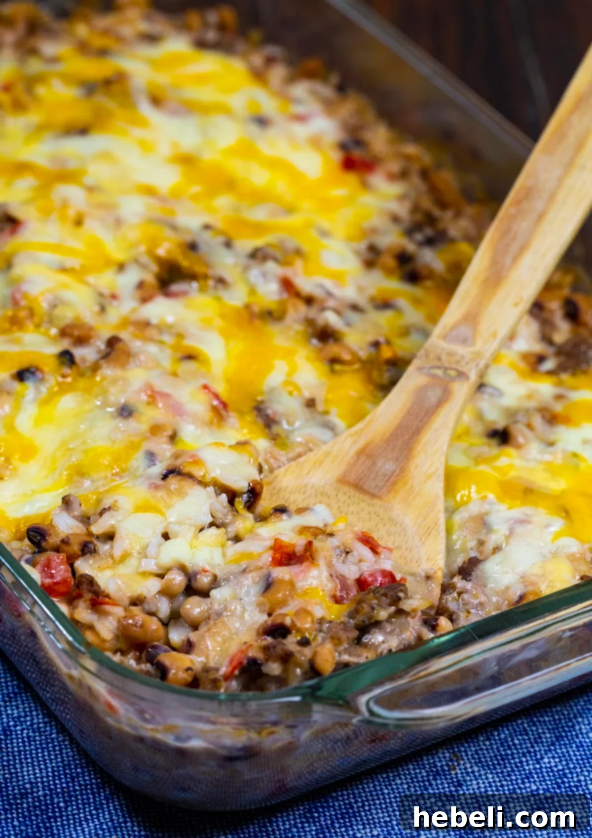 Southern Comfort Pea Bake 4 A wooden spoon scooping a portion of the Black-Eyed Pea Casserole, showing the creamy texture and melted cheese.