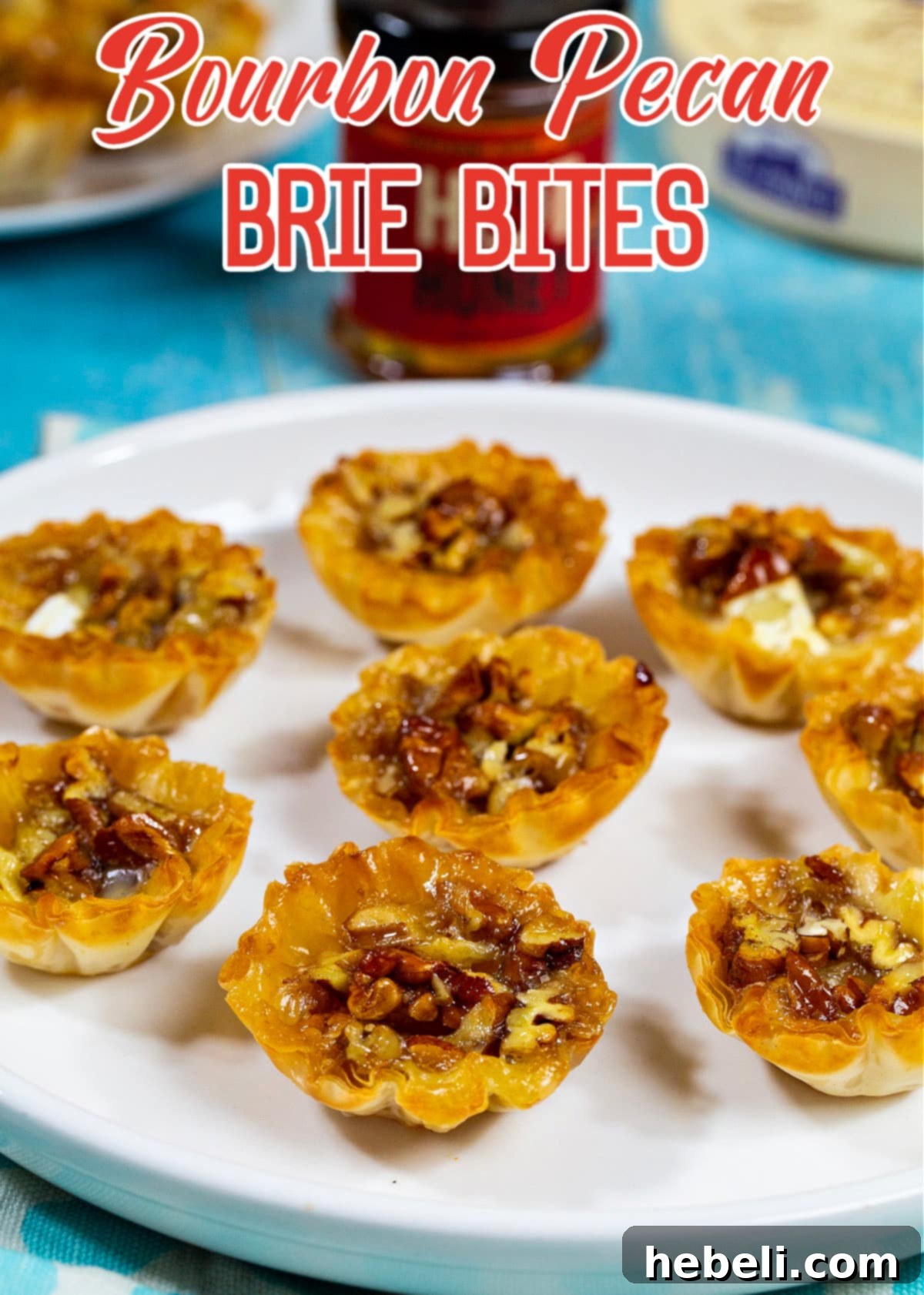 A single, perfectly baked Bourbon Pecan Brie Bite, highlighting the golden phyllo, melted brie, and sweet-spicy pecan topping.