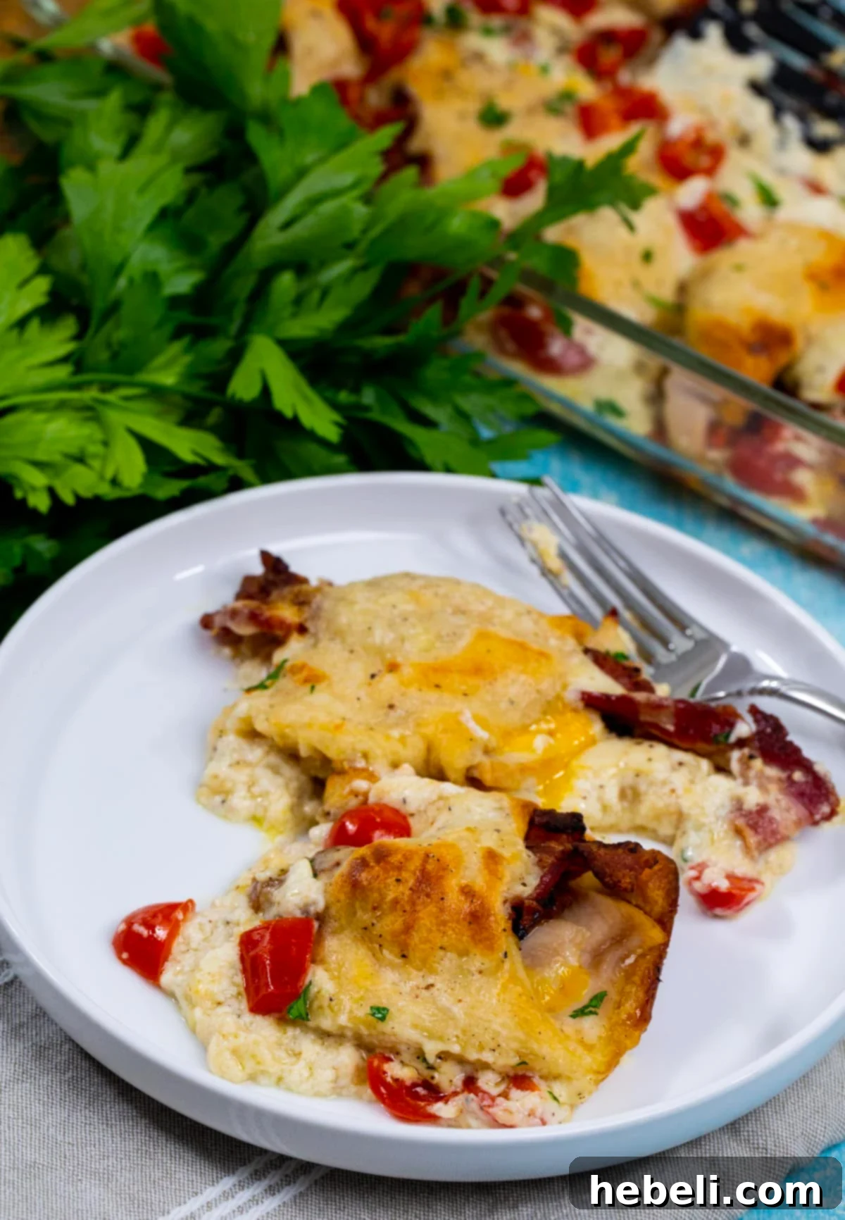 Kentucky Hot Brown Crescent Bake 7 A serving of Kentucky Hot Brown Crescent Casserole plated beautifully, showing a cut crescent roll filled with turkey and bacon, topped with rich sauce and a cherry tomato.