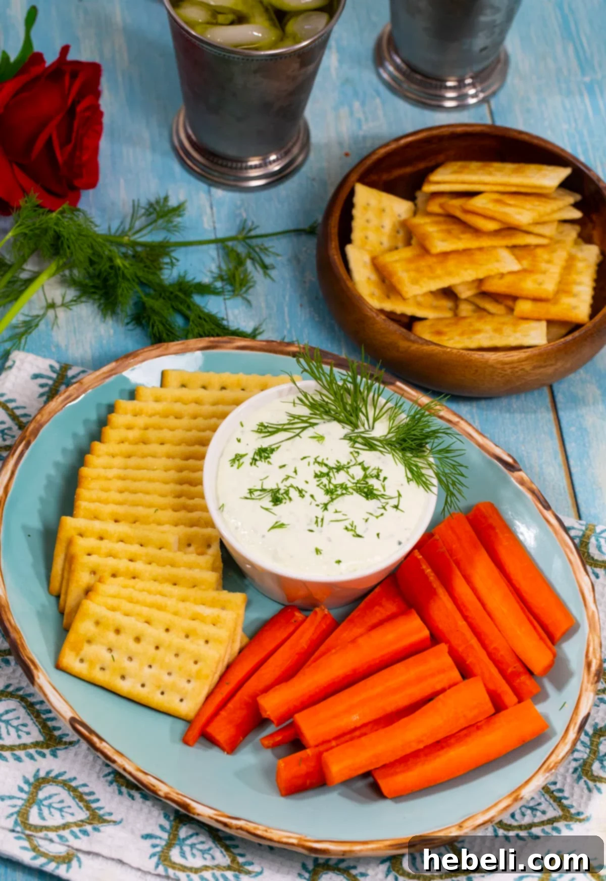 Benedictine Sandwich Spread 3 A refreshing Benedictine dip artfully arranged in a rustic bowl, accompanied by an assortment of crisp green crudités and savory crackers, ideal for any gathering.