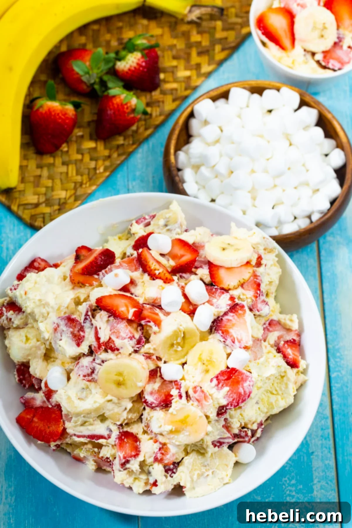 A bowl of Strawberry Banana Cheesecake Salad with a separate bowl of mini marshmallows, ready to be combined.