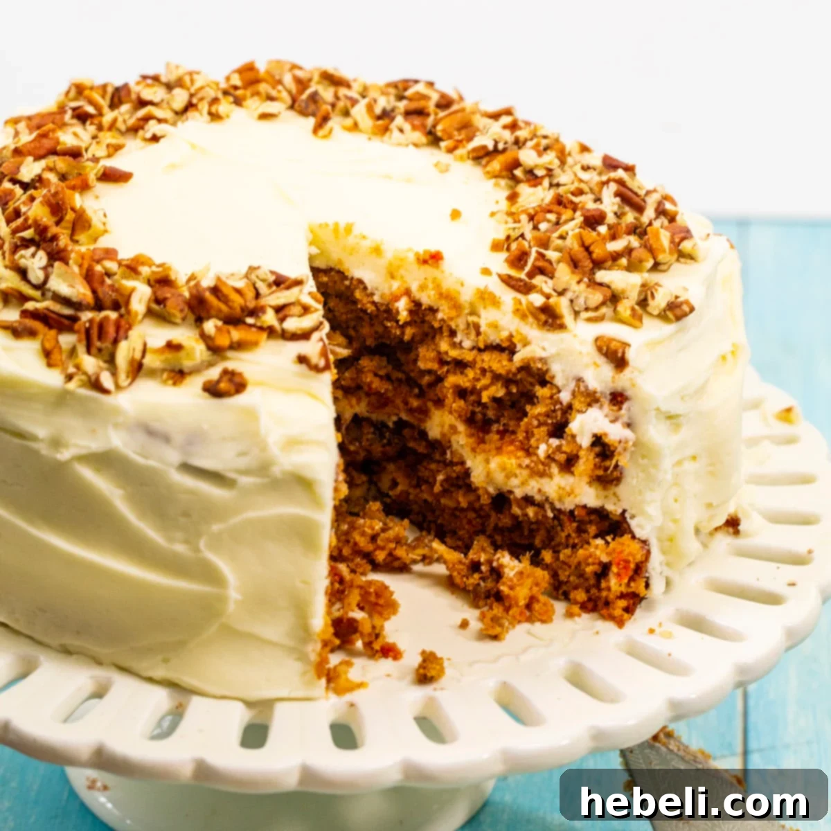 Carrot cake with a slice already cut out, revealing the moist interior and thick layer of cream cheese frosting.