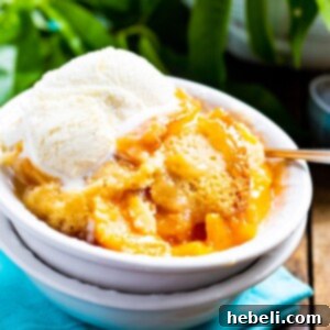 Slow Cooker Peach Cobbler topped with vanilla ice cream in a bowl, ready to serve and enjoy.