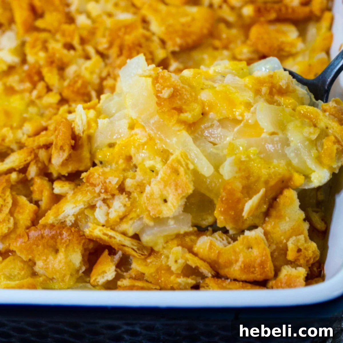Spoon scooping up Vidalia Onion Casserole, showcasing the creamy filling and golden-brown cracker topping.