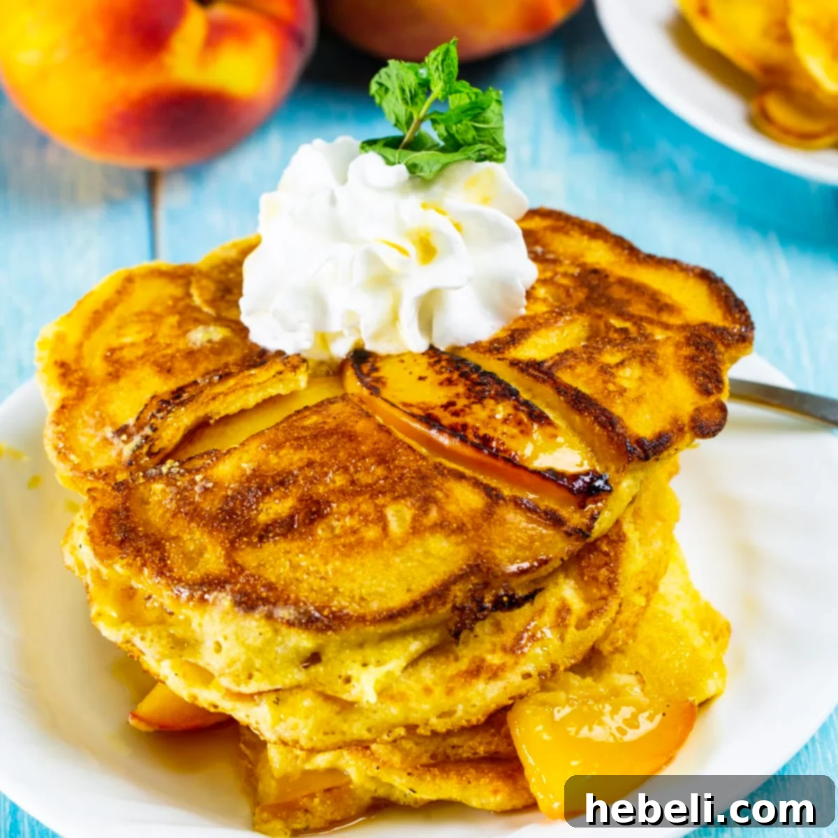 Sweet Peach Pancakes topped with a generous dollop of whipped cream and a drizzle of maple syrup.