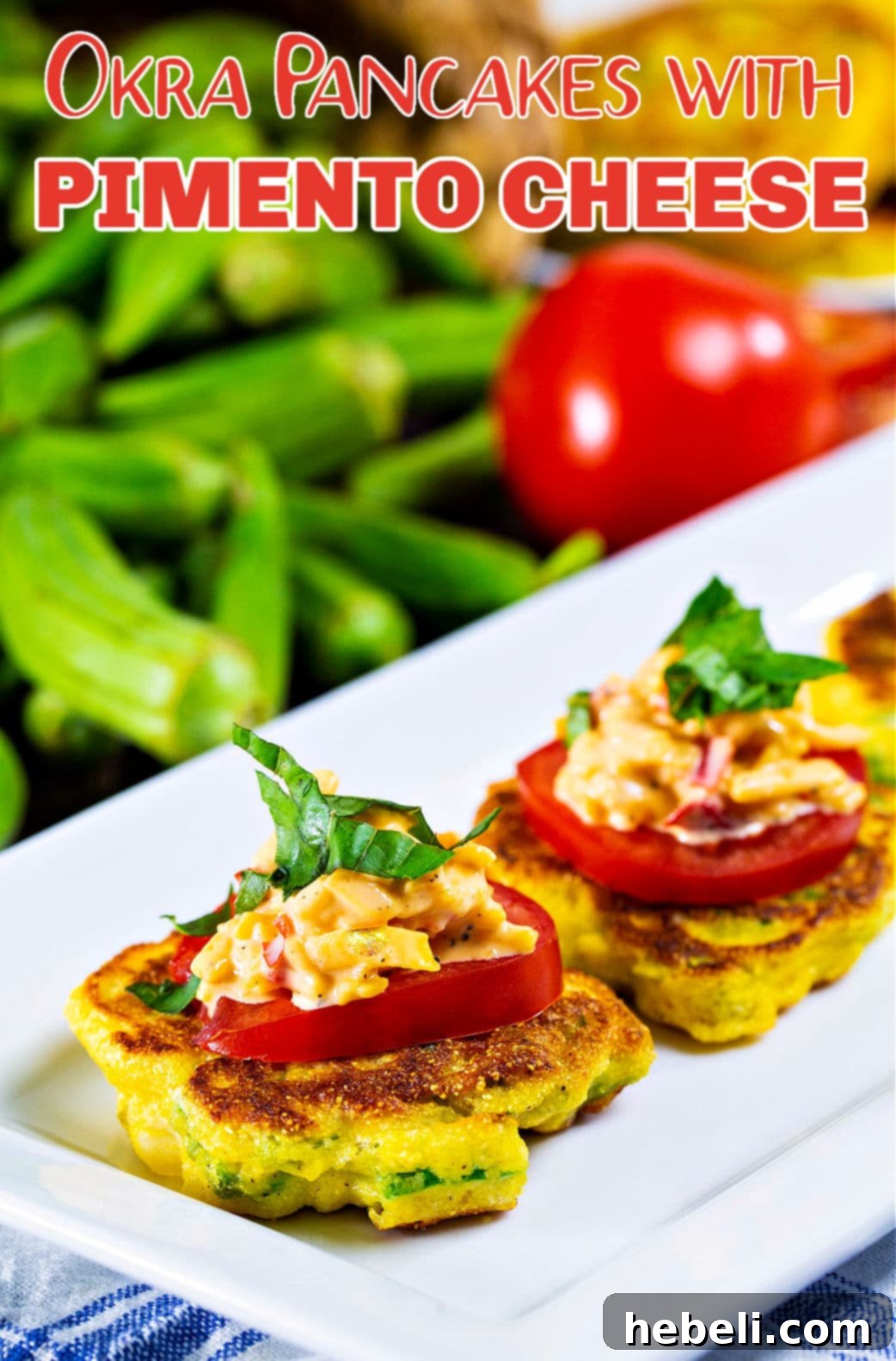 Appetizer pancakes with okra, pimento cheese, and tomato slices on a white serving plate, garnished with fresh herbs.