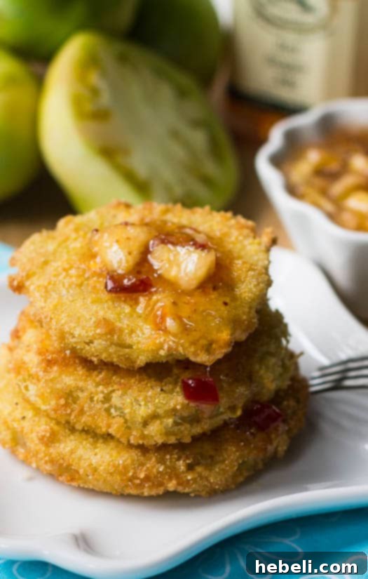 Peach Pepper Glazed Fried Green Tomatoes 3 A close-up of a single crispy Fried Green Tomato with a dollop of peach pepper jelly sauce on top.