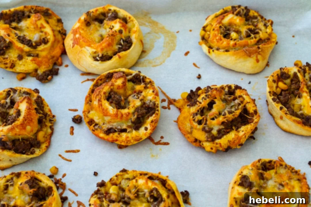 Fiesta Pizza Rolls 5 Freshly baked Taco Pizza Rolls with golden crusts and melted cheese, straight from the oven on a baking sheet.