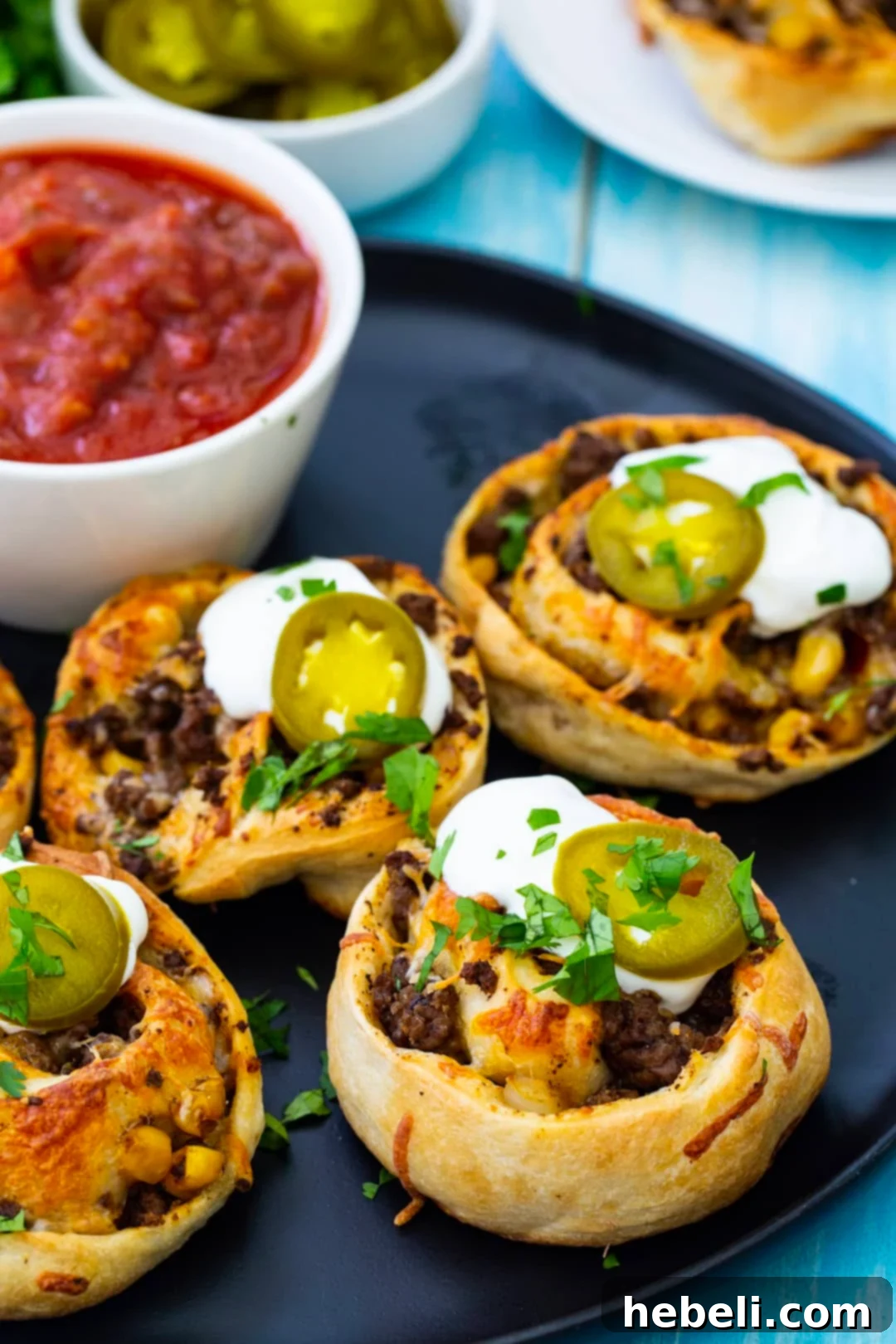 Fiesta Pizza Rolls 6 Close-up of golden Taco Pizza Rolls garnished with a dollop of sour cream and fresh cilantro.