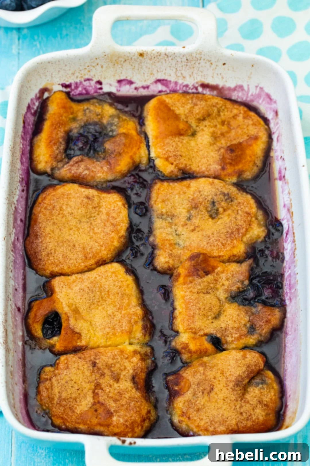 Unbaked blueberry dumplings carefully arranged in a clear glass baking dish, waiting to be baked to golden perfection.