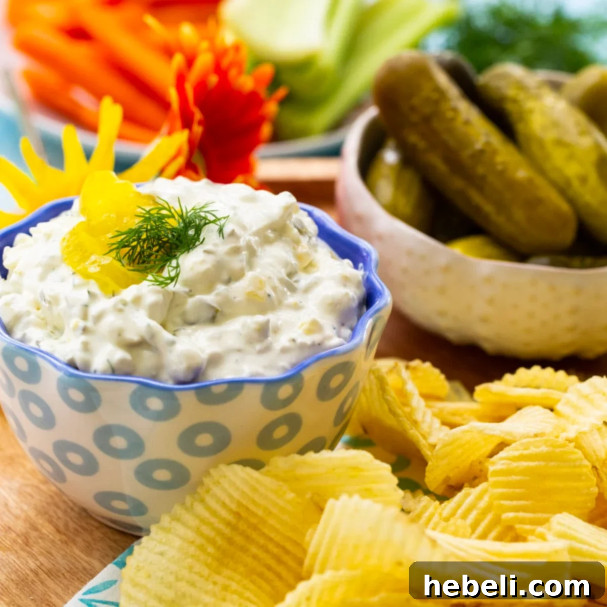 A vibrant bowl of creamy Dill Pickle Dip, garnished with fresh dill, surrounded by an assortment of crispy chips and crackers, ready for a party.