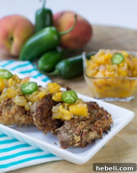 Pork Medallions topped with Spicy Peach Chutney on serving platter with peaches and jalapenos in background.