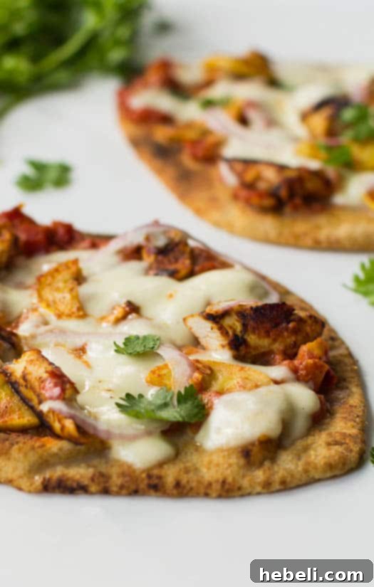 Close-up view of a freshly baked Chicken Tikka Naan Pizza, highlighting the delicious toppings and golden crust.