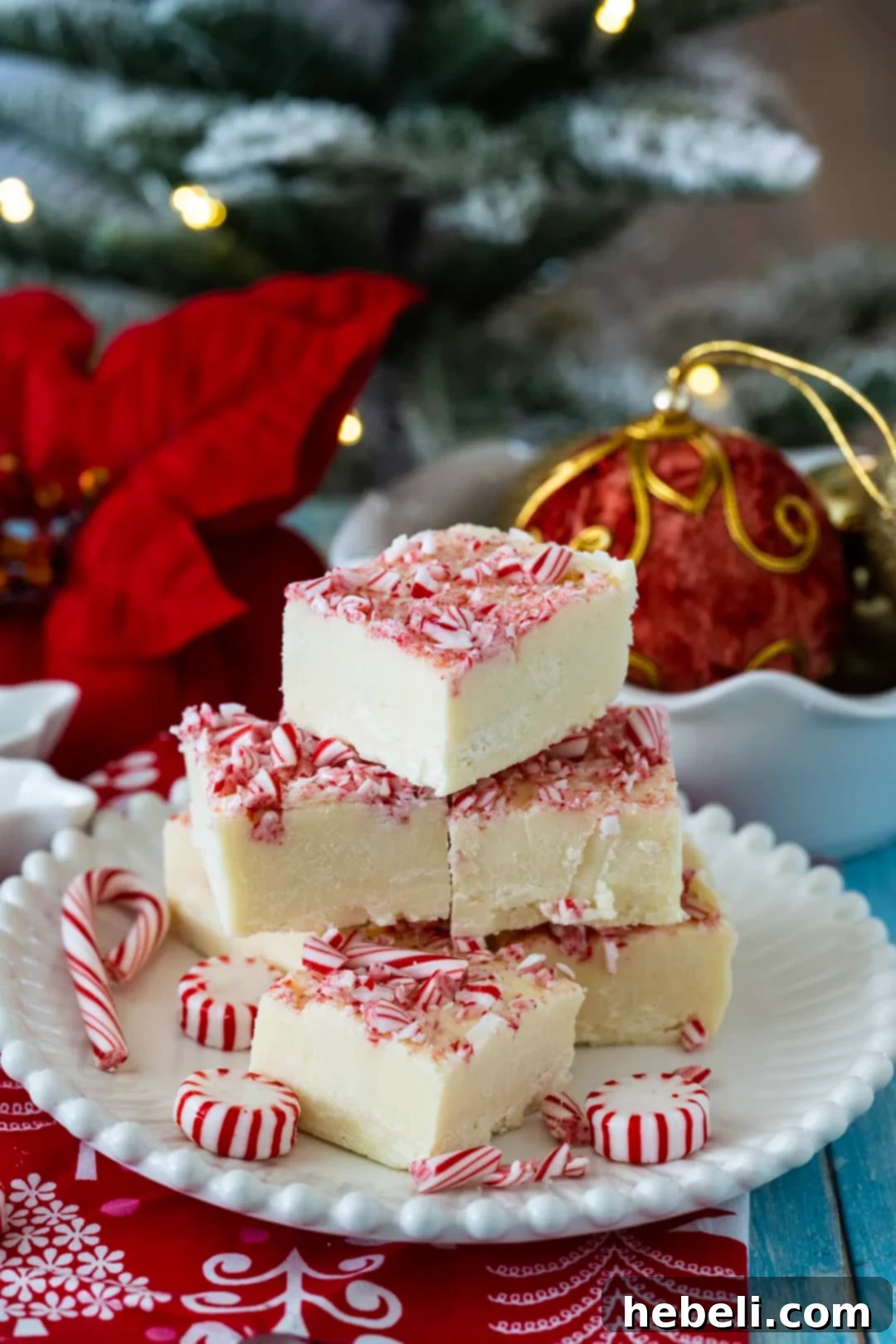 Peppermint Cloud Fudge 5 A festive holiday spread featuring Peppermint White Chocolate Fudge on a plate with Christmas decorations in the background.