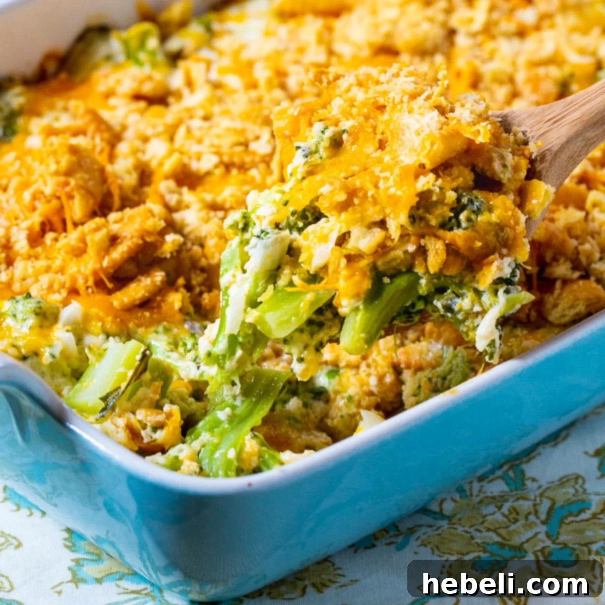 Wooden spoon scooping up Southern Broccoli Casserole, showcasing its creamy texture and golden-brown topping.