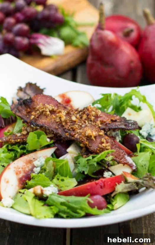 Vibrant Apple and Pear Salad with Maple Pecan Bacon, a perfect fall dish served in a large white bowl, garnished with fresh herbs.