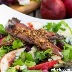 Beautifully plated Apple and Pear Salad with Maple Pecan Bacon and Cranberry Vinaigrette, ready to serve as a festive autumn dish.