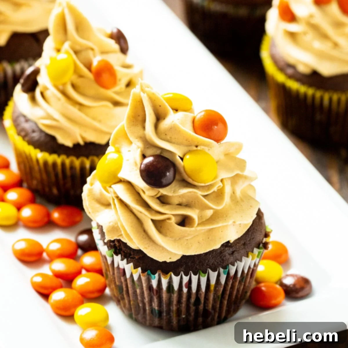 Chocolate Reese's Cupcakes topped with peanut butter frosting on a serving platter, adorned with Reese's Pieces.