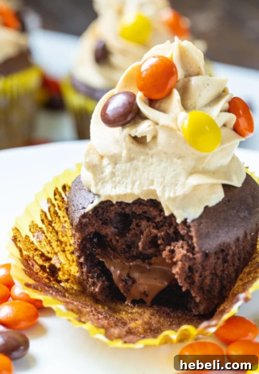 A chocolate Reese's cupcake with a bite taken out, revealing the hidden peanut butter cup inside.