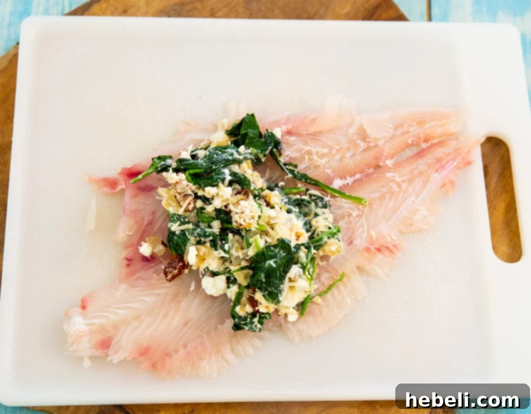 Flounder Fillets Stuffed with Creamy Spinach 4 Filling mounded on middle of fish, demonstrating how to prepare the flounder for rolling.