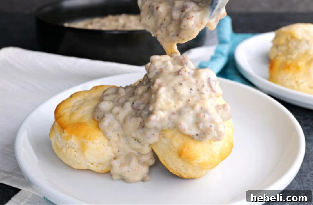 Sausage gravy being generously spooned over biscuits, a classic Southern breakfast.