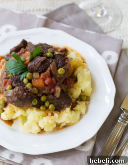 Effortless Slow Cooker Provencal Beef Daube 4 A generous serving of authentic Beef Daube Provencal, featuring tender beef and vibrant vegetables, served over fluffy mashed potatoes.