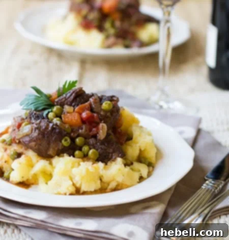Effortless Slow Cooker Provencal Beef Daube 5 Close-up of Slow Cooker Beef Daube Provencal served generously over fluffy mashed potatoes on a pristine white plate.