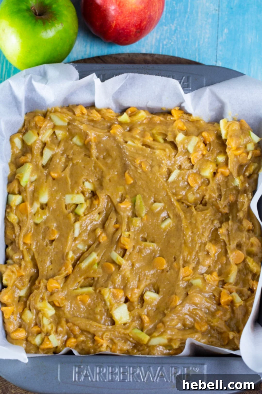 Unbaked butterscotch apple bar batter evenly spread in a parchment-lined baking dish.
