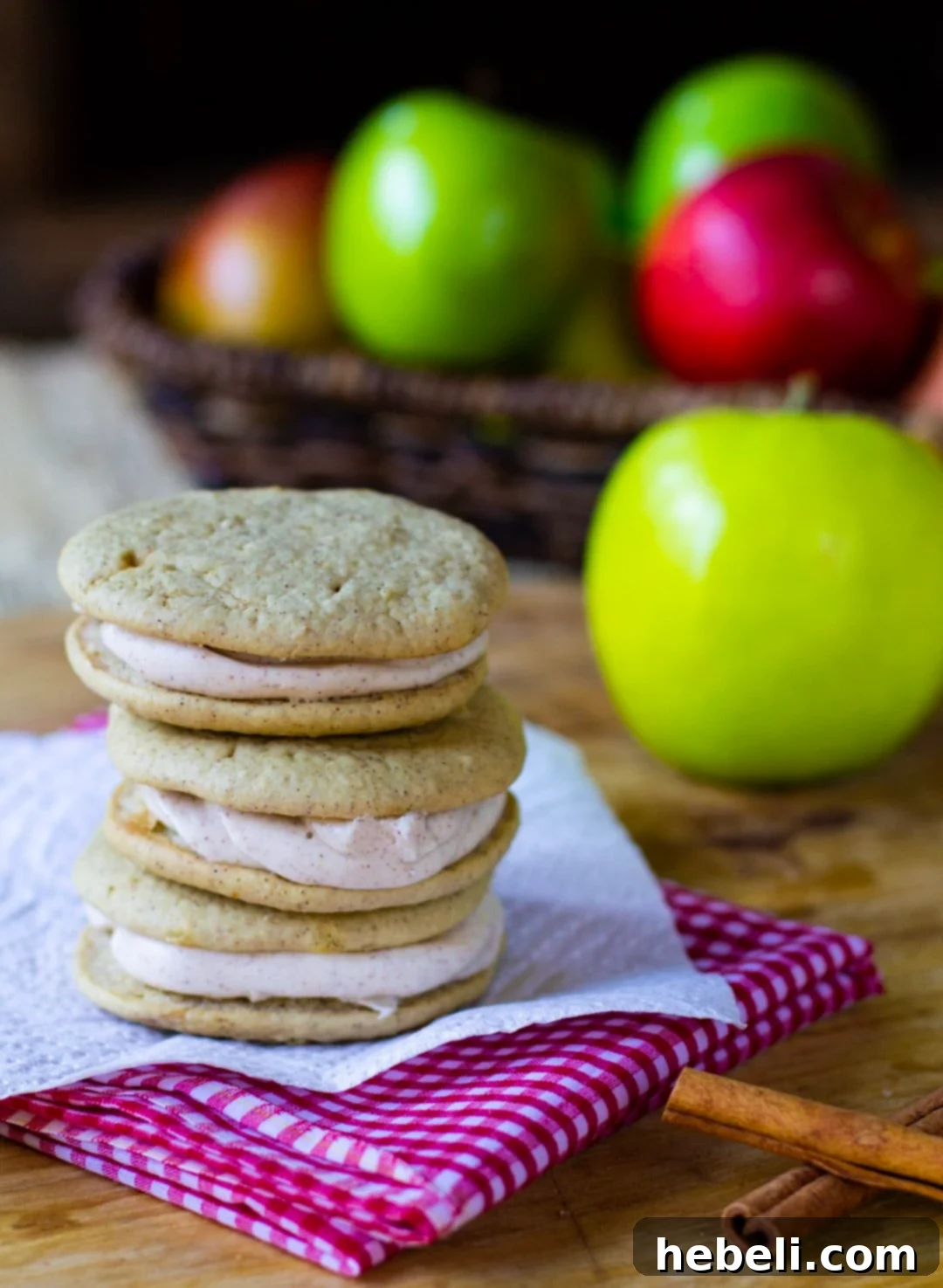 Spiced Apple Whoopie Delights 3 Freshly baked Apple Spice Whoopie Pies arranged on a plate with vibrant fresh apples in the background, highlighting the seasonal inspiration.