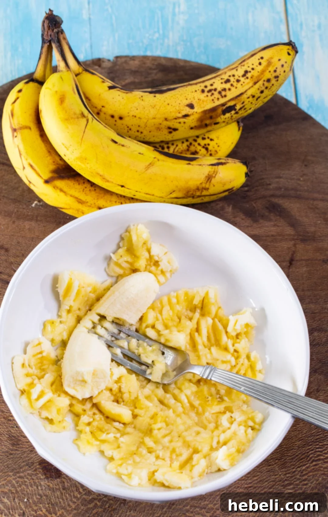 Decadent Chocolate Glazed Banana Bread 5 Overripe banana being mashed with a fork in a bowl.