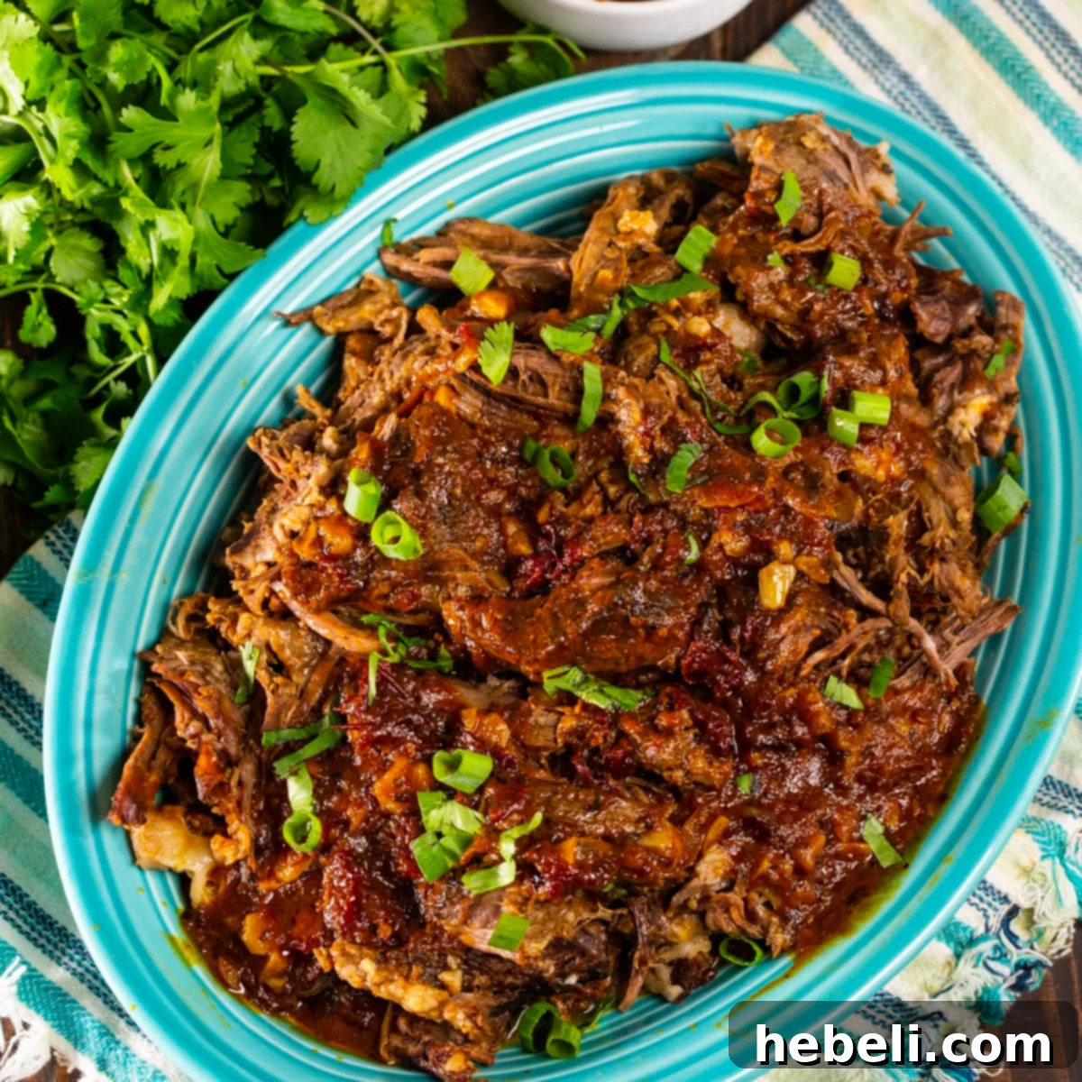 Delicious Chipotle Beef for Tacos, shredded and ready to serve on a rustic platter, garnished with fresh cilantro.