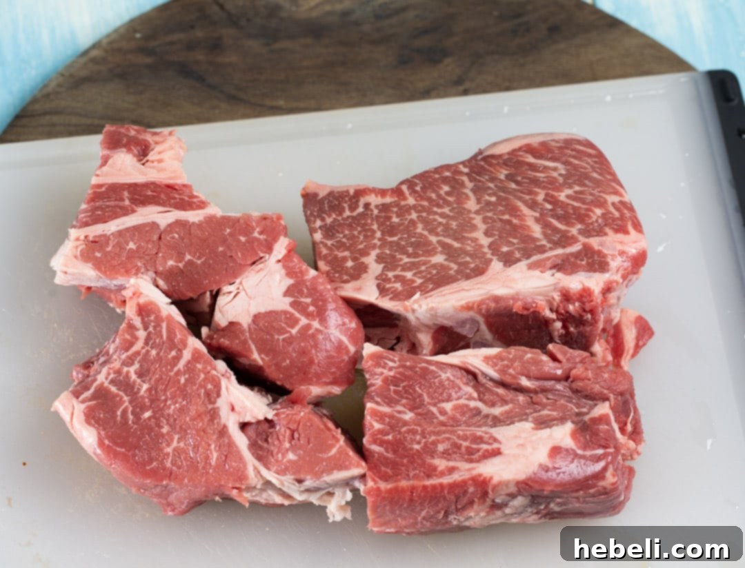 A boneless beef chuck roast, expertly cut into four substantial, equal-sized pieces, prepared for cooking.