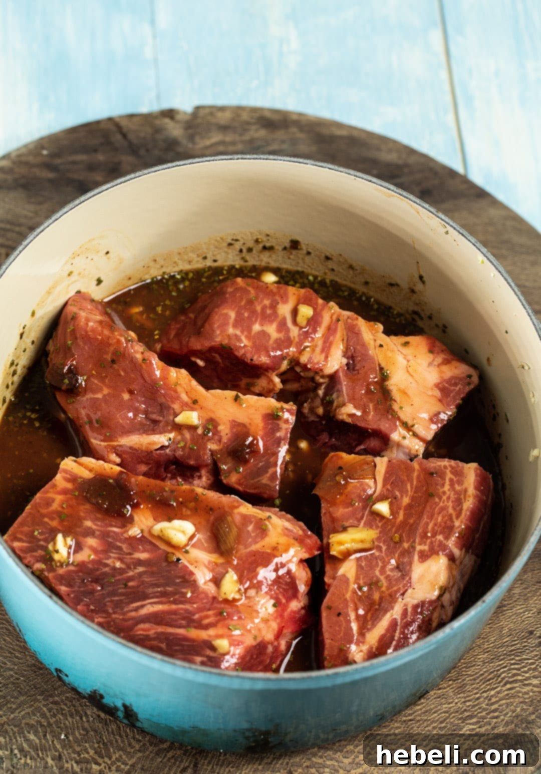 Uncooked chuck roast pieces thoroughly coated in the rich, smoky chipotle sauce, ready for the slow cooking process.