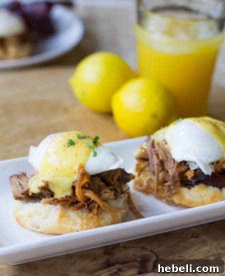 Southern Eggs Benedict on a biscuit with pulled pork. Orange juice and lemons in background.