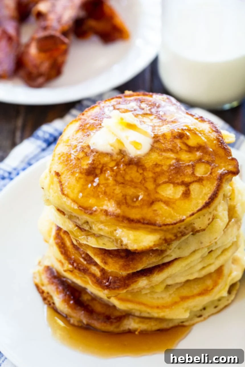 Fluffy Buttermilk Pancakes 9 Overhead view of several golden, fluffy buttermilk pancakes stacked on a white plate, garnished with fresh berries.