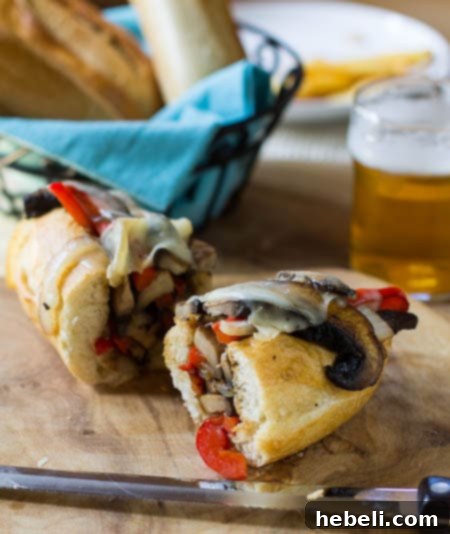 Portobello Cheesesteak Sandwiches 3 Portobello Cheesesteak cut in half with beer and bread in background.