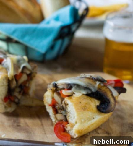 Portobello Cheesesteak Sandwiches 4 Half of a vegetarian Cheesesteak on a wood board with beer in background.