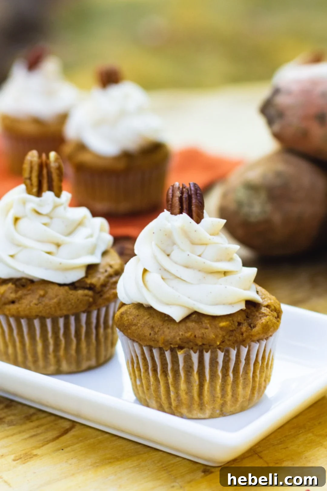 Close-up view of Sweet Potato Cupcakes with Spiced Buttercream, showcasing their fluffy frosting and perfectly baked texture, on a white serving tray.