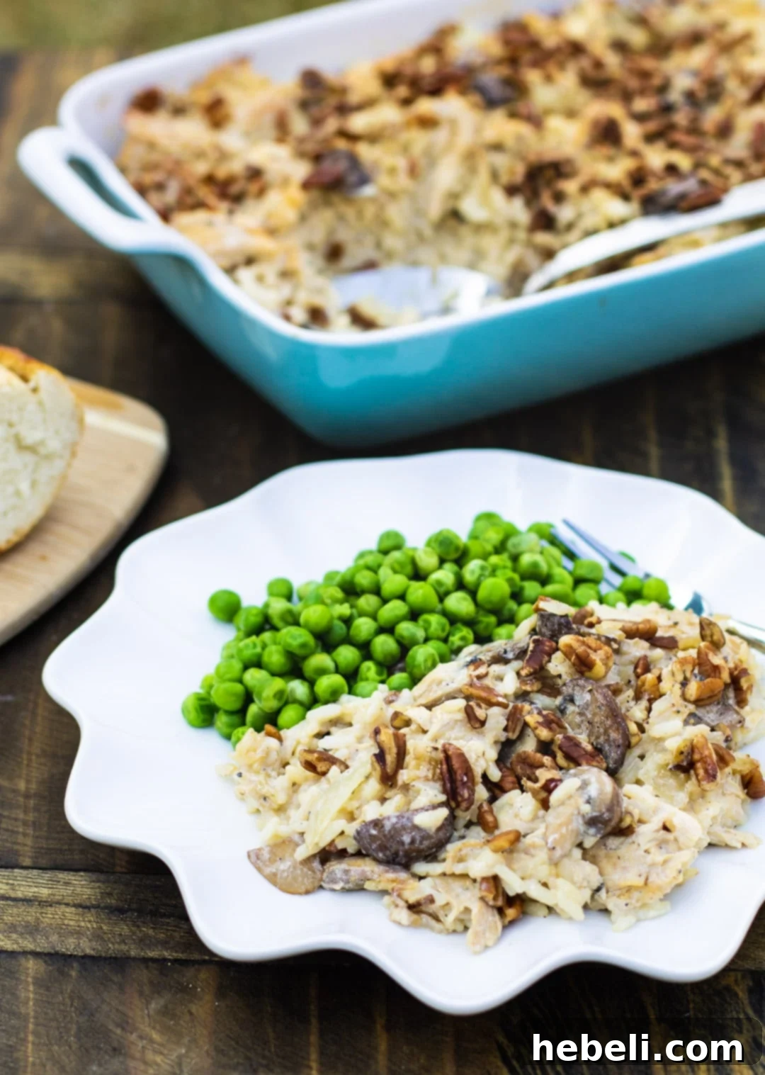 A large baking dish filled with golden-brown Chicken, Rice, and Mushroom Casserole, with a single serving plated beautifully beside it, ready to enjoy.