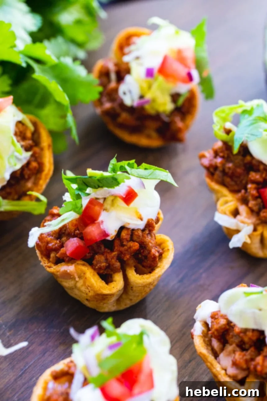 Mini Taco Bites artfully displayed on a wooden tray with a bunch of fresh cilantro for garnish.