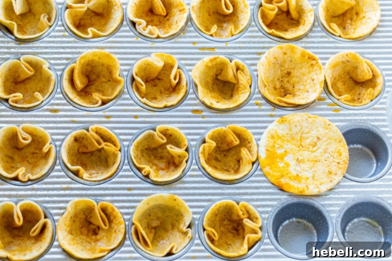 Process of pressing tortilla circles into a mini muffin tin to form taco shells.