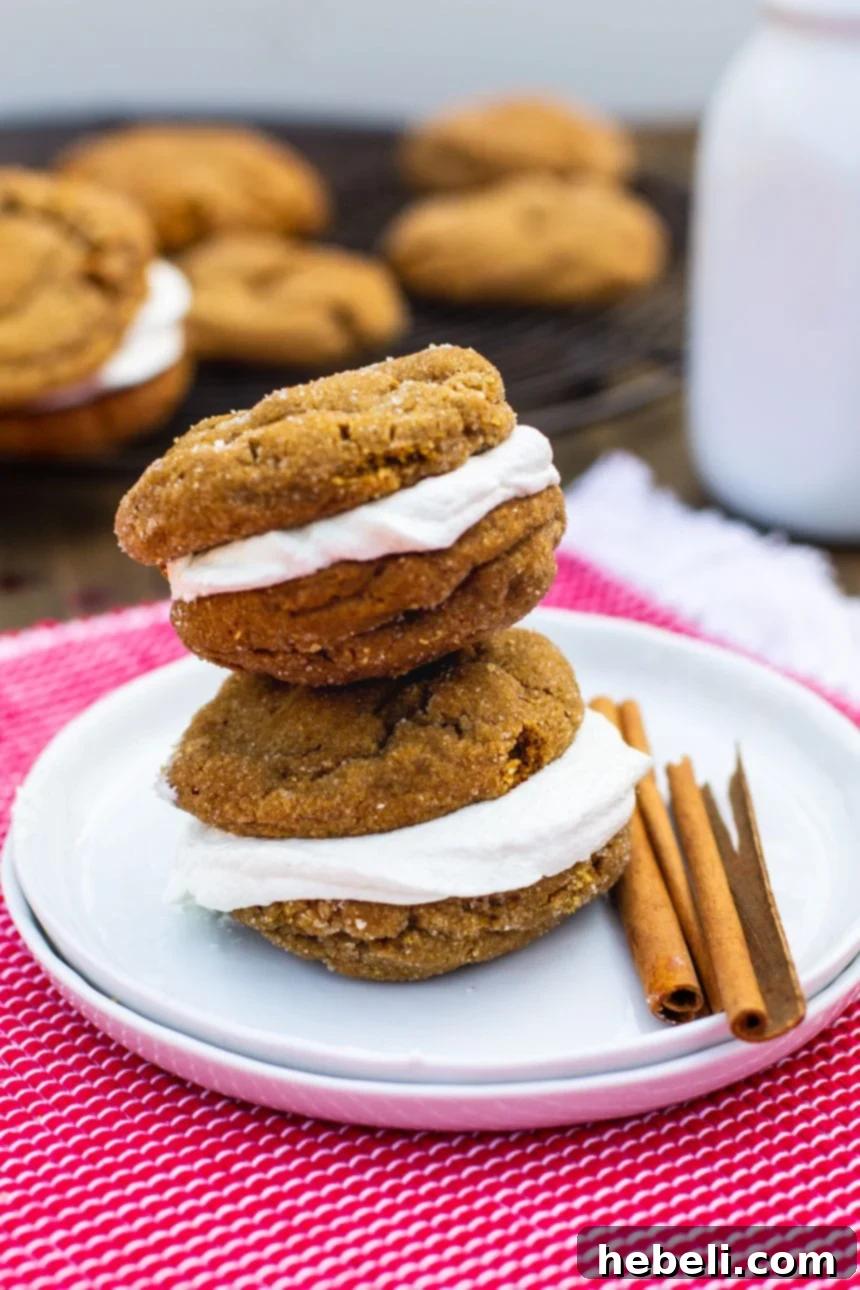 Two chewy gingerbread sandwich cookies on a small plate with cinnamon sticks and star anise, highlighting the festive spices.
