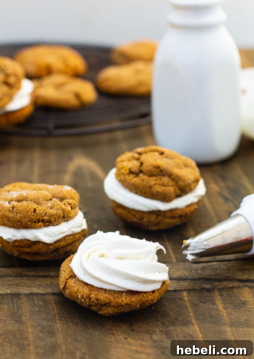 Piping the marshmallow filling onto the flat side of a gingerbread cookie.