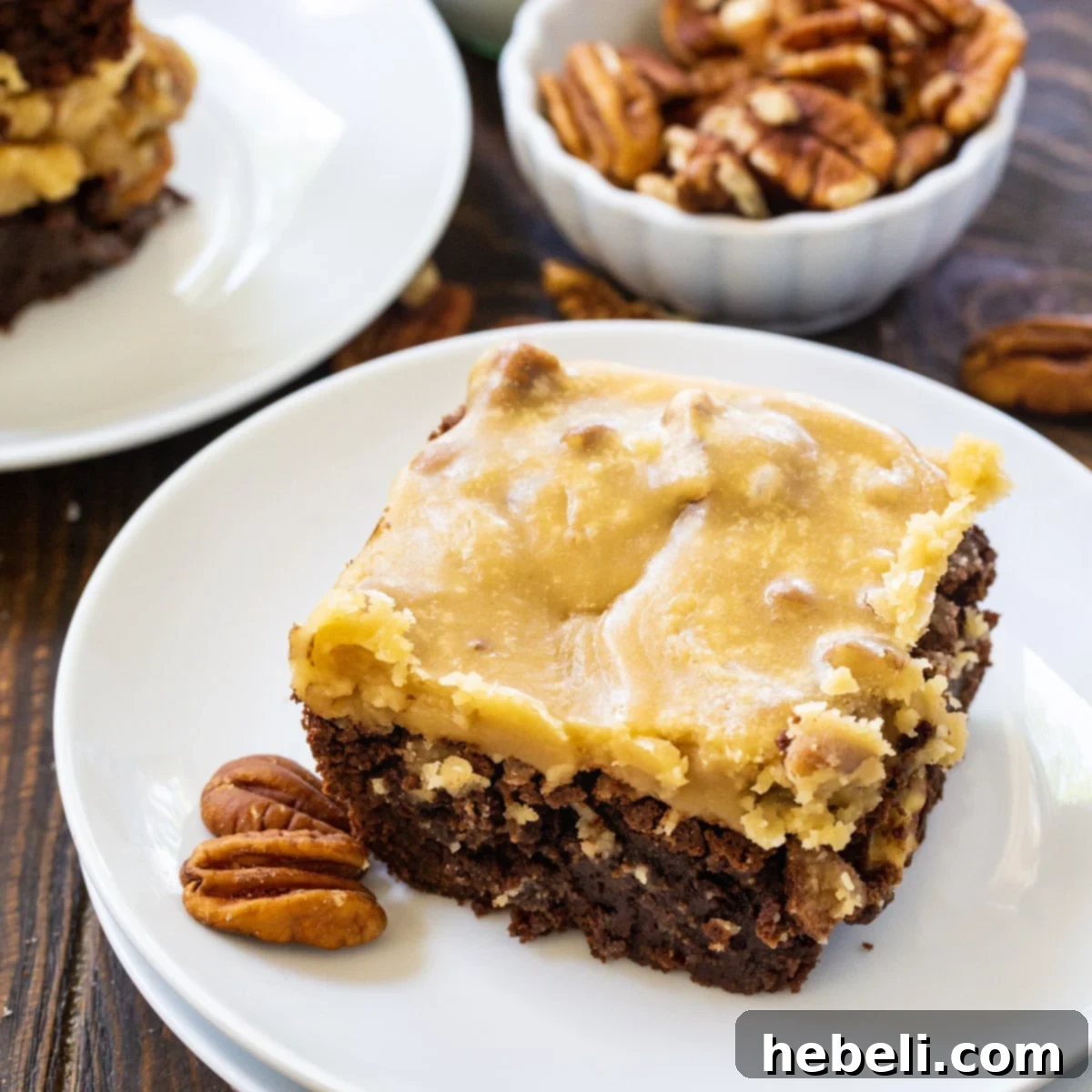 A single Praline Brownie on a white plate, showcasing its fudgy texture and caramel-pecan topping.