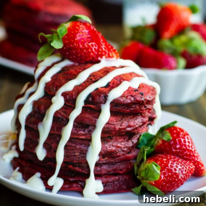 Stack of Red Velvet Pancakes on a plate, drizzled with cream cheese glaze.