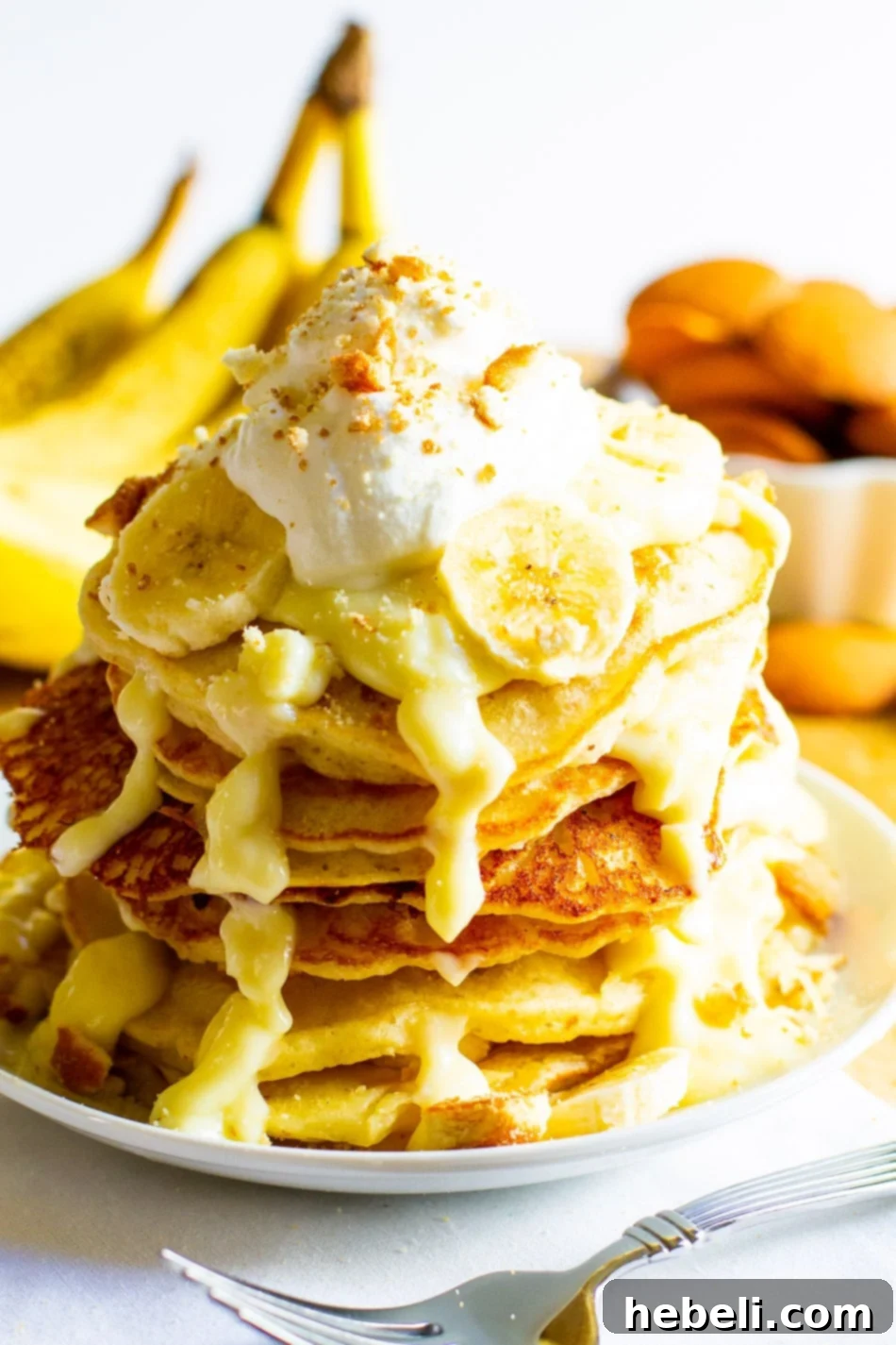 Decadent Banana Pudding Pancakes 3 Tall stack of Banana Pudding Pancakes generously topped with whipped cream and a sprinkle of vanilla wafer crumbs.