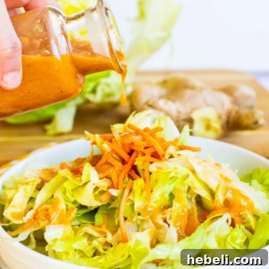 Zesty Ginger Vinaigrette 2 A vibrant green salad with shredded carrots being generously drizzled with homemade Japanese Steakhouse Ginger Salad Dressing.